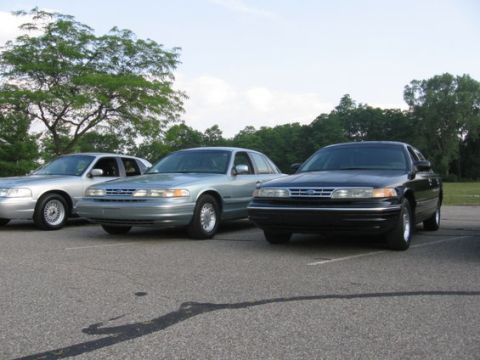 1988 Mercury Grand Marquis - Three Ford Crown Victorias are parked in a lot on a cloudy day.