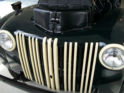 1996 Ford Bronco - Front view of a dark green vintage truck, a prominent cream-colored vertical grille and round headlights.