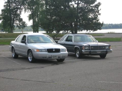 1988 Mercury Grand Marquis - A dark blue sedan from the late 1980s is parked next to a newer silver sedan.