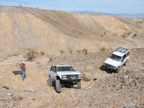 1997 Ford Ranger - Two SUVs navigate a challenging off-road course in a barren, mountainous terrain under a clear blue sky.
