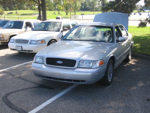 1988 Mercury Grand Marquis - Several Ford Crown Victorias are parked together, with one silver model having its hood open.