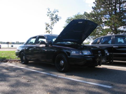 1988 Mercury Grand Marquis - A black Ford Crown Victoria Police Interceptor is parked with its hood open, next to another vehicle.