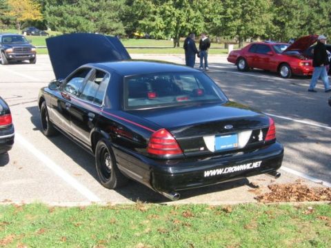 1988 Mercury Grand Marquis - A black sedan with its hood open is parked in a lot next to other vehicles.