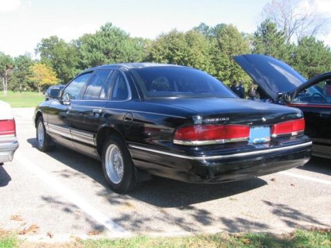 1988 Mercury Grand Marquis - Rear view of a black sedan parked in an outdoor lot with trees in the background.