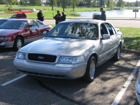 1988 Mercury Grand Marquis - A silver sedan is parked in a lot next to other vehicles, with a body style indicative of a 2000s model.