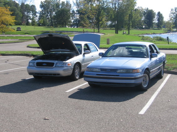 Blue 1988 Mercury Grand Marquis parked next to a silver sedan with hood open