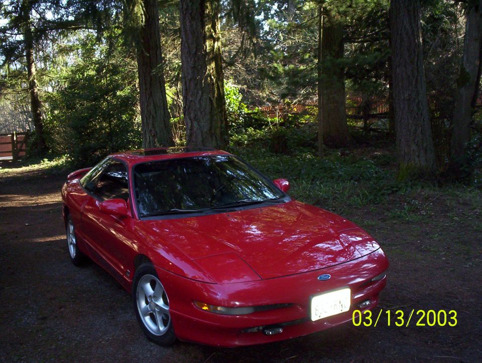 Red 1993 Ford Probe parked outside with trees in the background