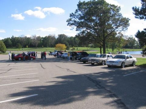 1988 Mercury Grand Marquis - A gathering of cars in a parking lot on a sunny day, with a white 1988 Mercury Grand Marquis prominently displayed.