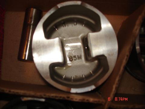 1994 Ford Probe - A close-up view of a metal piston with visible markings, resting in a box.