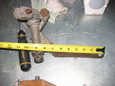 1992 Ford Bronco - A metal bracket is shown with a tape measure and a screwdriver, indicating its dimensions.