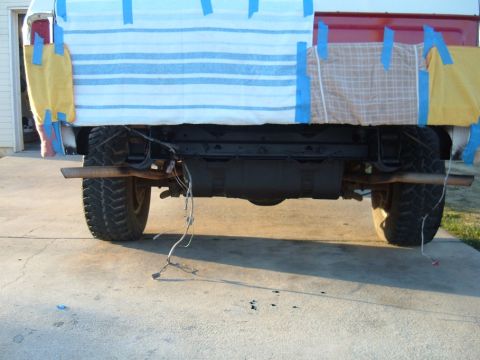 1978 Ford Bronco - Rear view of a truck's axle and exhaust system, with the bed covered by fabric panels.