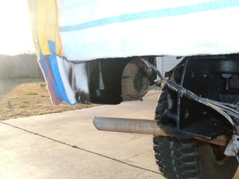 1978 Ford Bronco - Close-up of a vehicle's rear exhaust pipe and undercarriage, partially obscured by a towel.