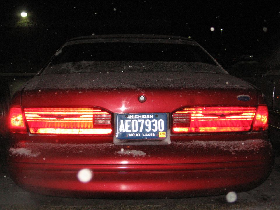 Rear view of a red 1995 Ford Thunderbird with snow on it. Michigan license plate AE07930