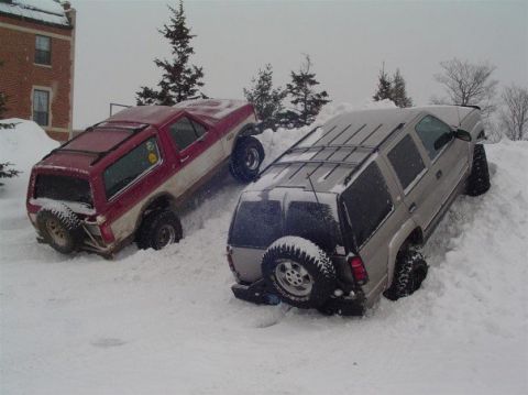 2000 Chevrolet Tahoe - Two SUVs are stuck in deep snow on a snowy slope.
