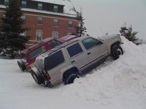 2000 Chevrolet Tahoe - Two SUVs are stuck in a deep snowdrift, with one vehicle partially submerged.