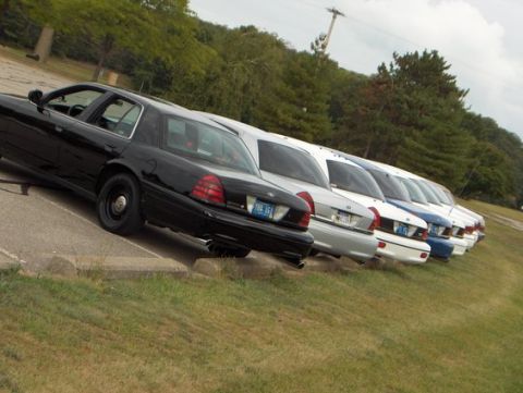 1988 Mercury Grand Marquis - A row of sedans, including a black model with steel wheels, parked on a grassy incline.