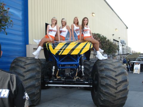1994 Ford Bronco - Four women in Hooters attire pose atop a monster truck with yellow and black striped graphics.