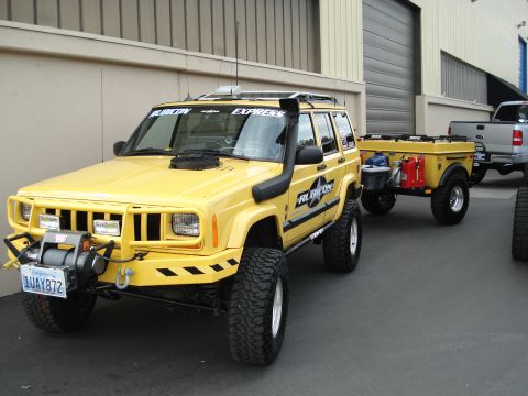 1994 Ford Bronco - Modified yellow Jeep Cherokee XJ with a trailer, seen at an outdoor event.