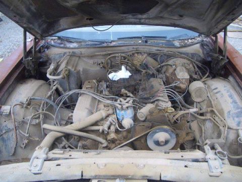 1974 Ford Ranchero - The engine bay of a vehicle, showing a V8 engine covered in dust and grime.