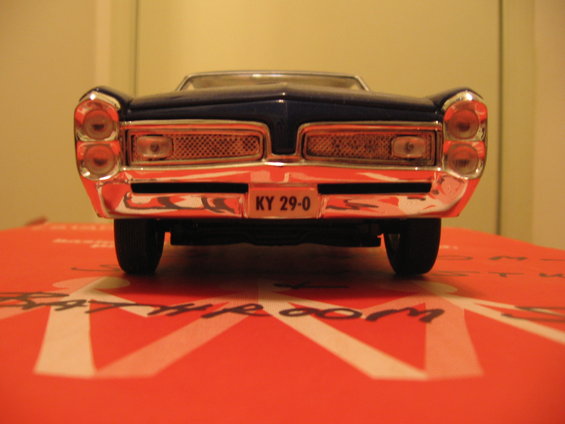 Front view of a dark blue diecast model convertible car on a printed surface