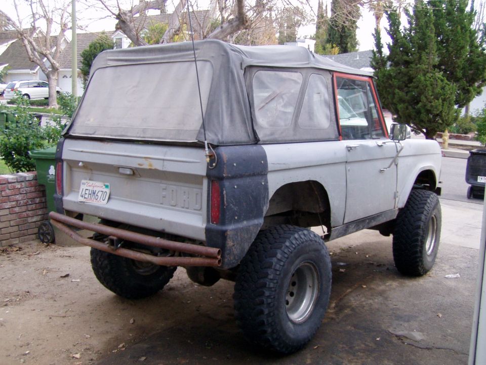 Gray Ford Bronco with soft top, lifted suspension, and aftermarket rear bumper
