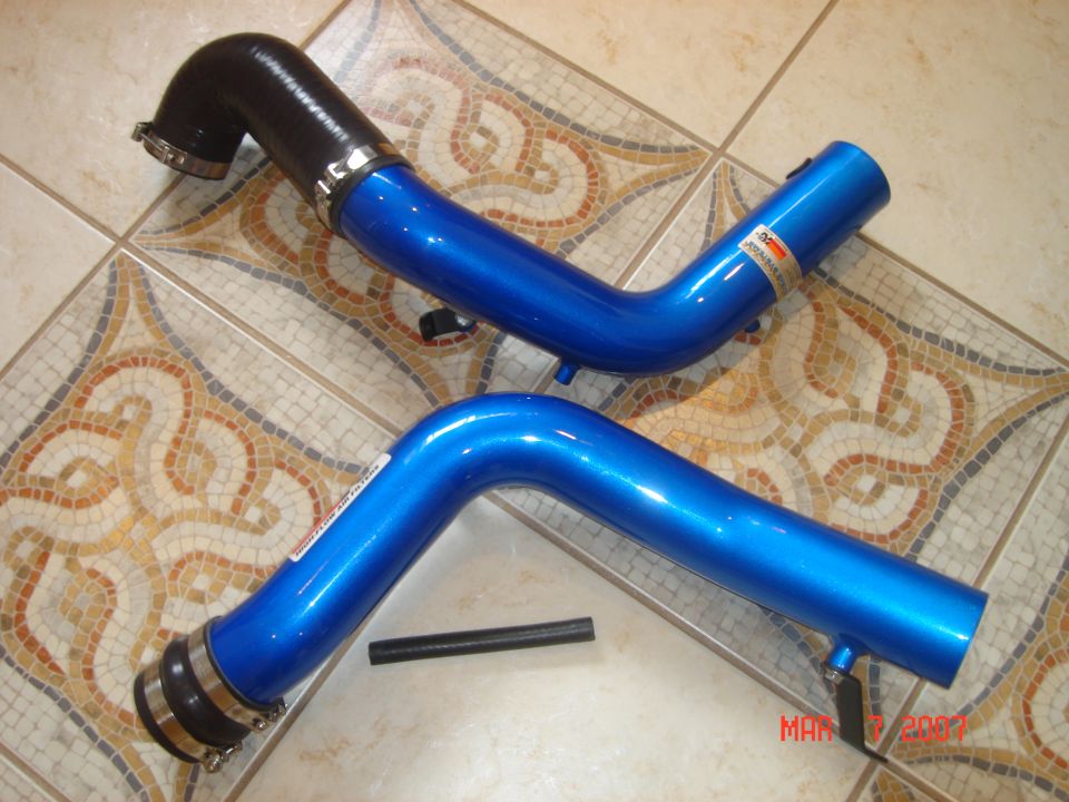 Pair of blue aftermarket charge pipes with black silicone couplers on a tile floor