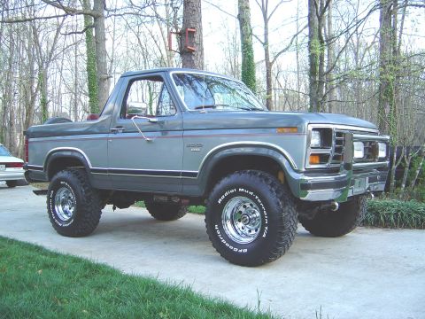 1986 Ford Bronco - Front three-quarter view of a clean two-tone gray full-size Ford Bronco with its hardtop removed, lifted on chrome wheels and BFGoodrich Mu…