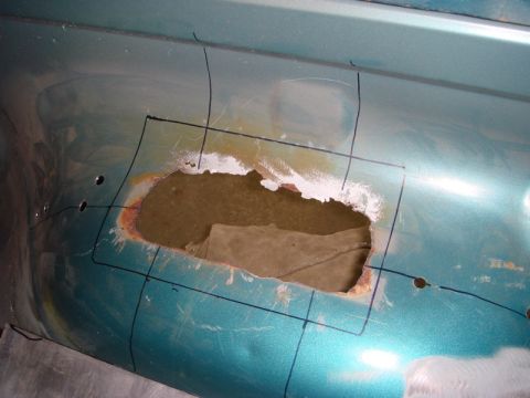 1996 Ford Bronco - A section of a teal vehicle's body panel shows significant rust damage and has been marked for repair.