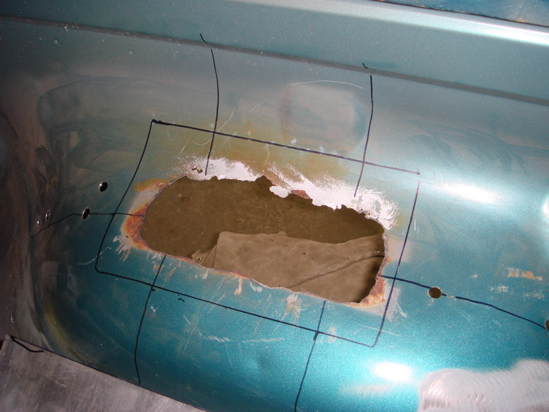 teal vehicle panel with large rust hole, marked with black lines for repair