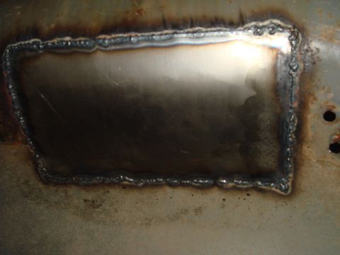 1996 Ford Bronco - A rectangular metal patch has been welded into a rusted surface, showing signs of repair work.