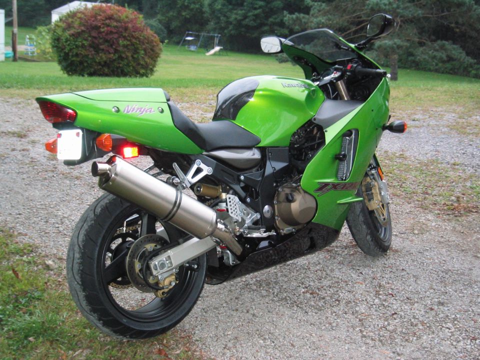 Green Kawasaki Ninja sportbike parked on gravel, rear three-quarter view