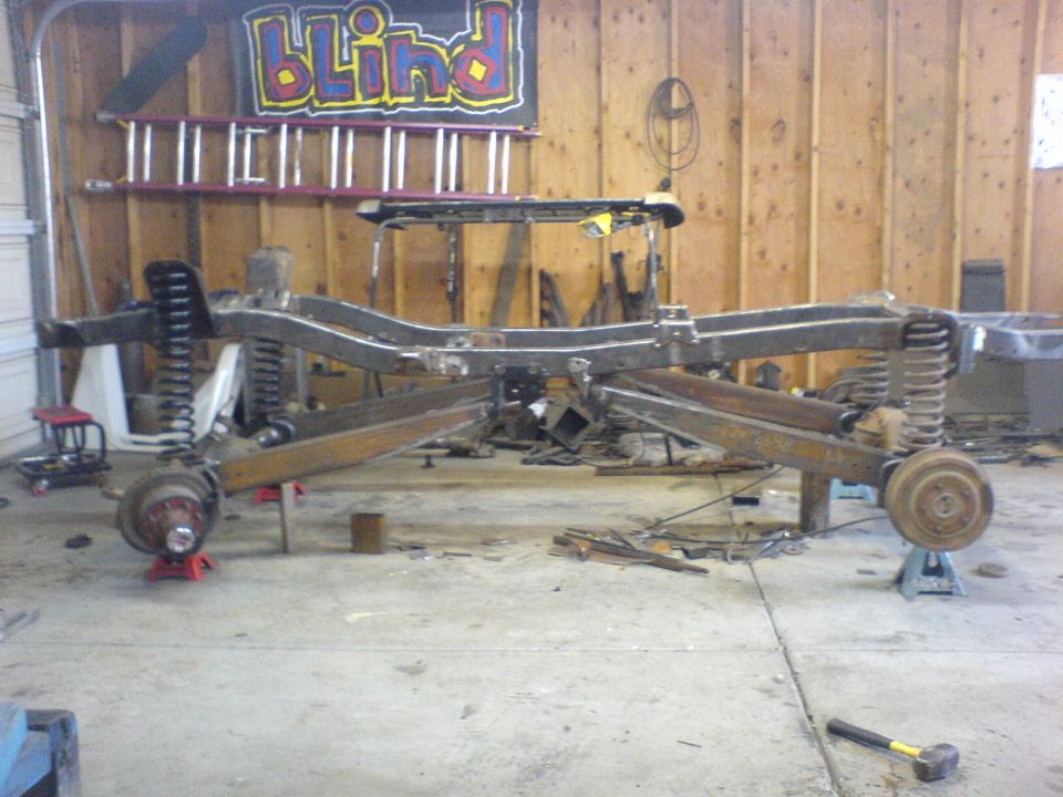 Vehicle frame and suspension assembly on jack stands in a garage