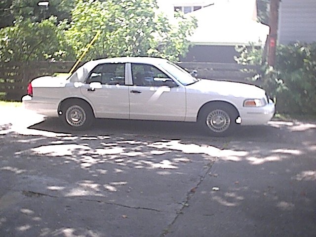 White Crown Victoria sedan side profile parked in a residential driveway