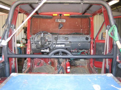 1987 Suzuki Samurai - The interior of a red 1987 Suzuki Samurai is visible, a roll cage, dashboard, and a fire extinguisher.
