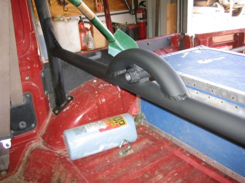 1987 Suzuki Samurai - Close-up of a vehicle's interior, showing a roll cage and storage area. A can of spray paint is on the floor.