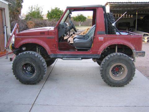 1987 Suzuki Samurai - This modified Suzuki Samurai is shown from the side with its doors off and large off-road tires installed.