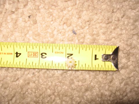 1990 Ford Bronco - A small gear is measured against a tape measure on a carpeted surface.
