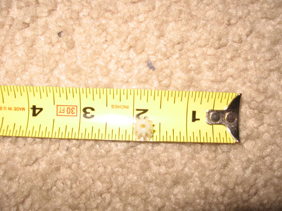 Small white gear next to a tape measure showing 1.5 inches