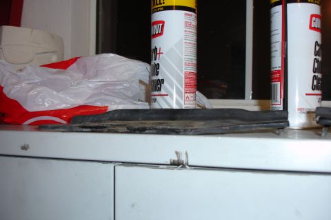 1996 Ford Bronco - A rubber trim piece sits on a shelf next to two cans of automotive cleaner.