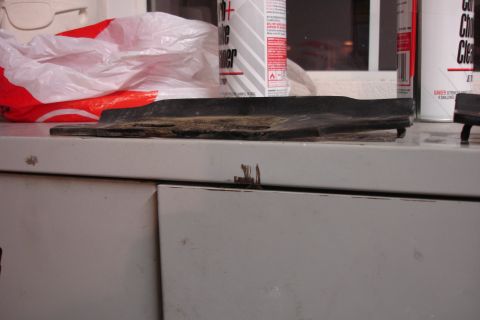 1996 Ford Bronco - A damaged rubber trim piece rests on a workbench, with cleaning supplies in the background.