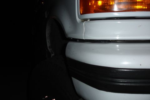 1996 Ford Bronco - A close-up shot of a white vehicle's front end, focusing on the bumper and headlight assembly.