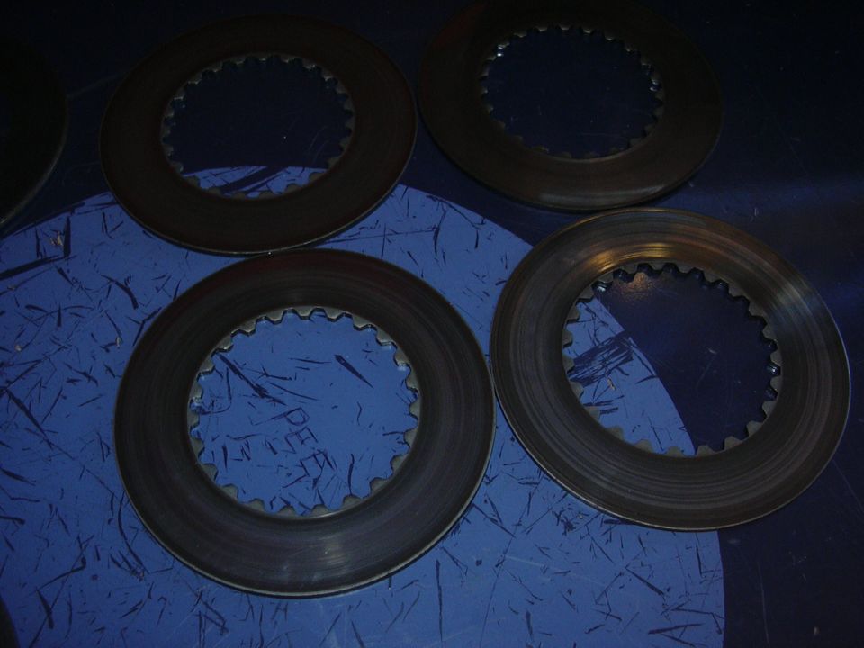 Four differential clutch packs with toothed inner edges on a blue surface