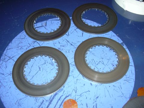 1996 Ford Crown Victoria - Four clutch discs are laid out on a blue surface, possibly for a vehicle's transmission.