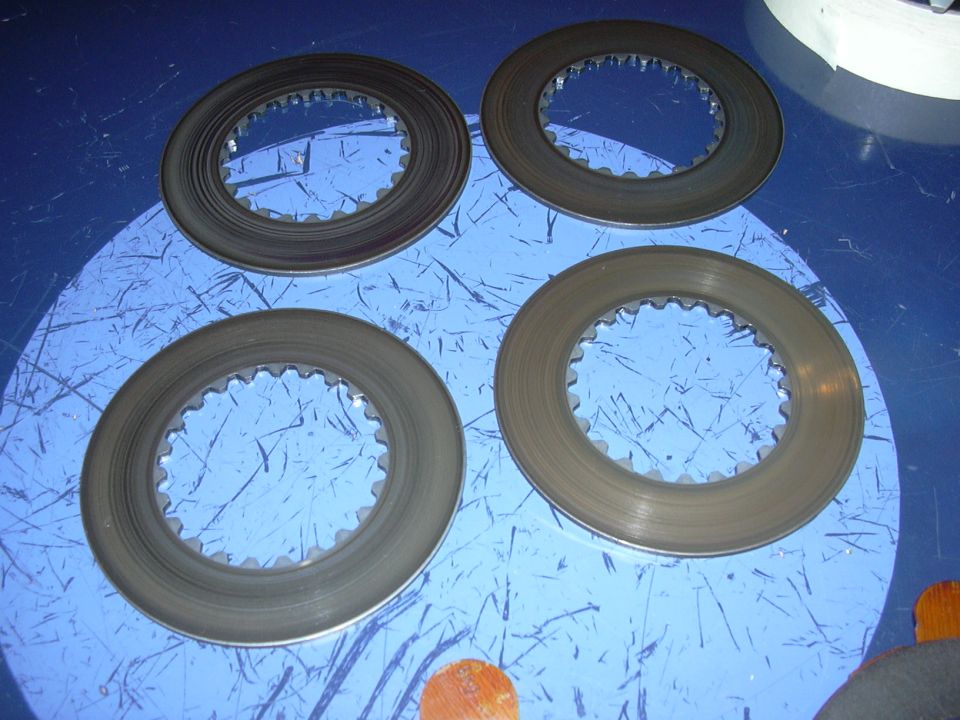Four clutch discs with toothed inner edges on a blue surface