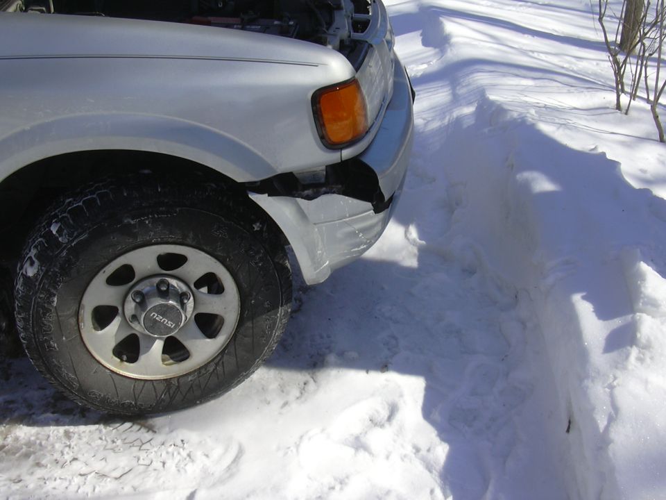 Silver SUV's front bumper is cracked and damaged, parked in snow with hood open