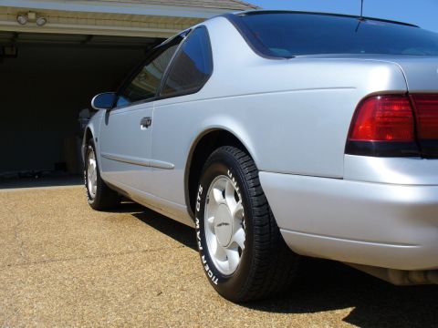 1995 Ford Thunderbird - Rear view of a silver 1995 Ford Thunderbird coupe parked in front of a garage.
