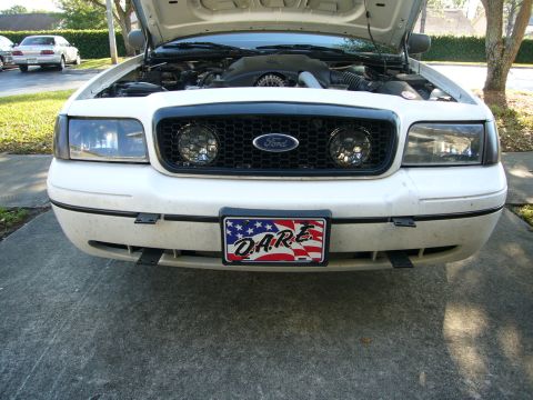 2000 Ford Crown Victoria - Head-on daylight view of a white Ford Crown Victoria on a driveway with the hood open, showing the honeycomb grille with Ford oval and mesh…