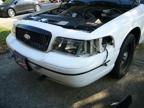 2000 Ford Crown Victoria - A white Ford Crown Victoria is shown from the front with its hood open and a push bumper attached.