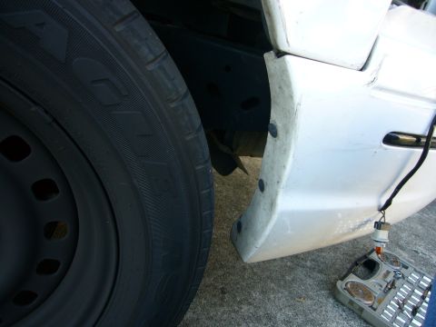 2000 Ford Crown Victoria - Close-up view of a white bumper section with black fasteners and a tire, possibly part of a push bumper installation.