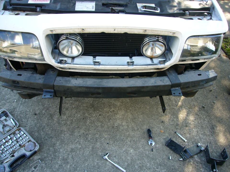 White 2000 Ford Crown Victoria front bumper with two auxiliary lights and tools scattered around